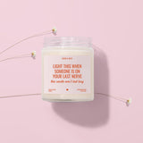 a candle labeled "LIGHT THIS WHEN SOMEONE IS ON YOUR LAST NERVE" with a heart symbol, placed on a pink background.