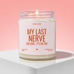 a candle labeled "My Last Nerve" with a flame, placed on a white pedestal against a pink background.