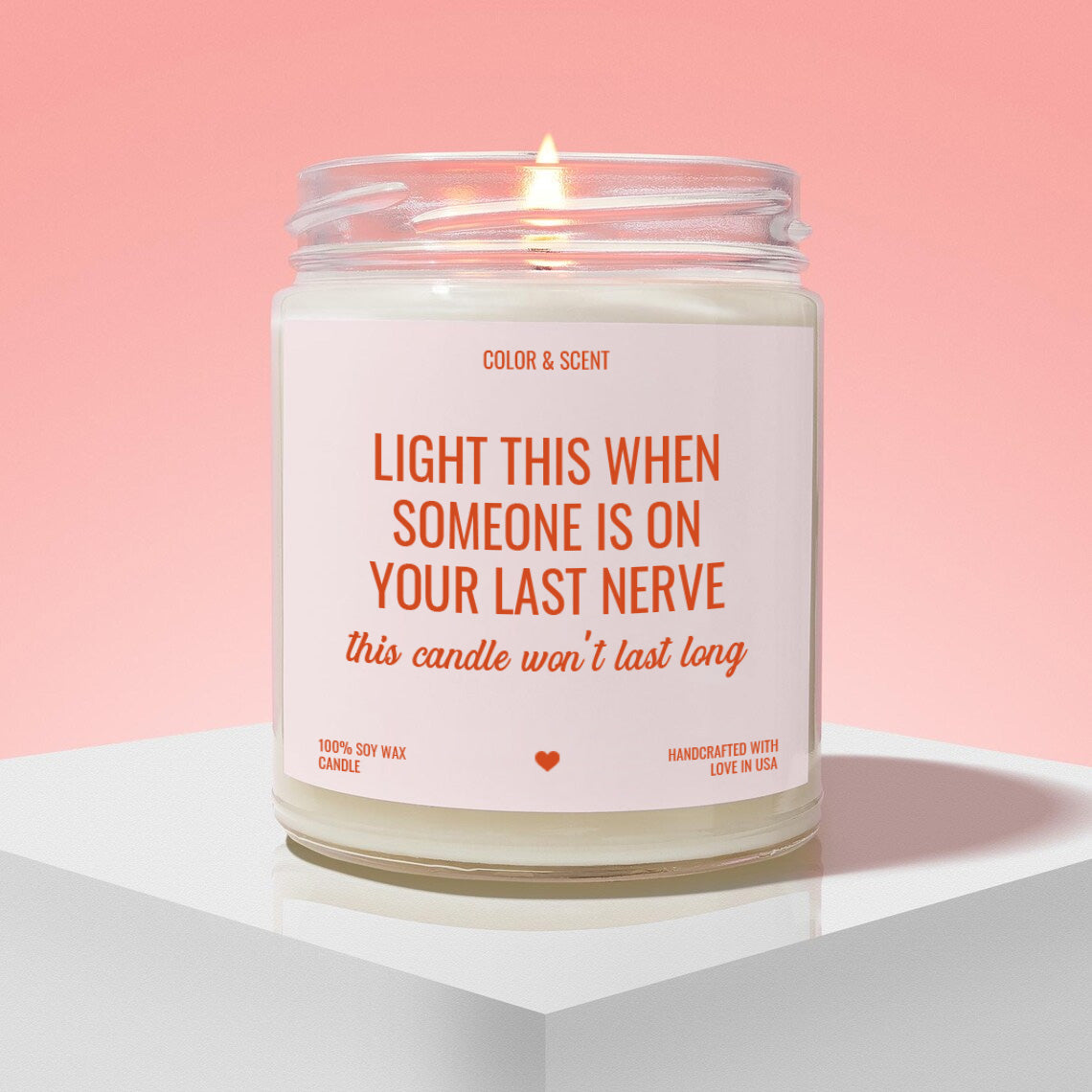 a white candle with a pink background, placed on a white surface. The candle has a label that reads "Light this when someone is on your last nerve" and "this candle won't last long".