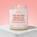 a white candle with a pink background, placed on a white surface. The candle has a label that reads "Light this when someone is on your last nerve" and "this candle won't last long".